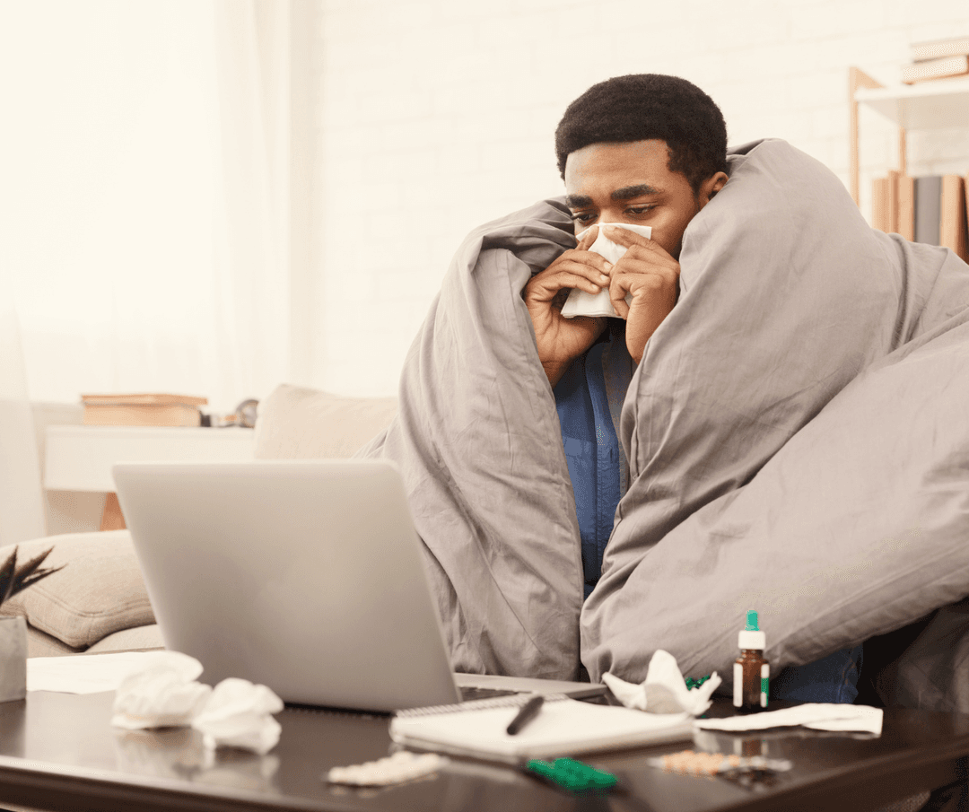 Sick patient coughing while resting in couch with a blanket.