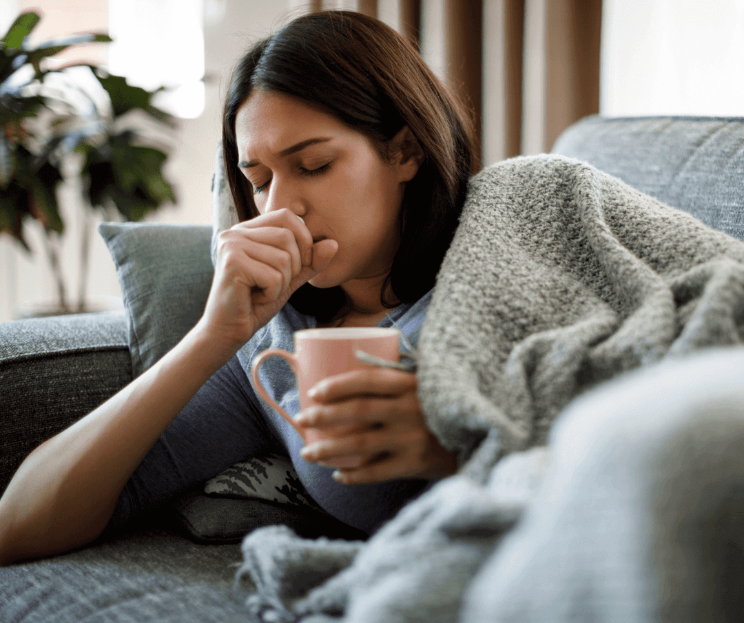 Sick patient coughing while resting in couch with a blanket.